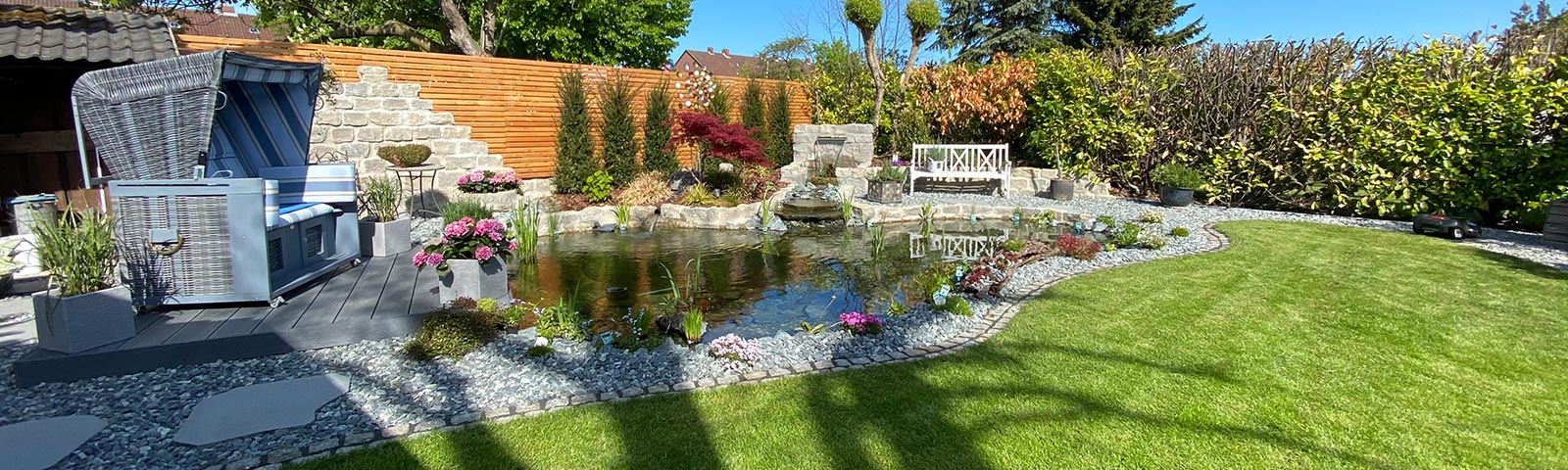 Garten mit Wasser, Sitzbank und bepflanztem Ufer