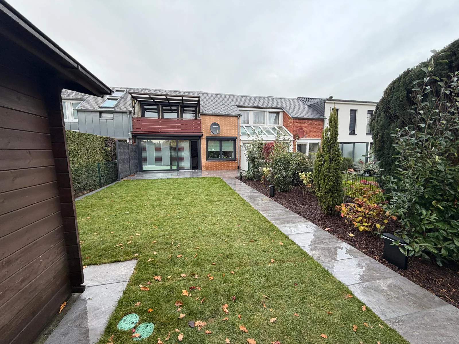 Neu gestalteter Reihenhausgarten in Hannover mit Rasen, Plattenweg und Terrasse